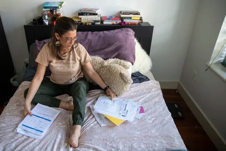 Stephanie Sena, 39, clears up a stack of medical bills from a foot amputation she had last fall. Sena is an adjunct professor at Villanova University with $20,000 in medical debt after learning her health plan didn't offer adequate coverage.