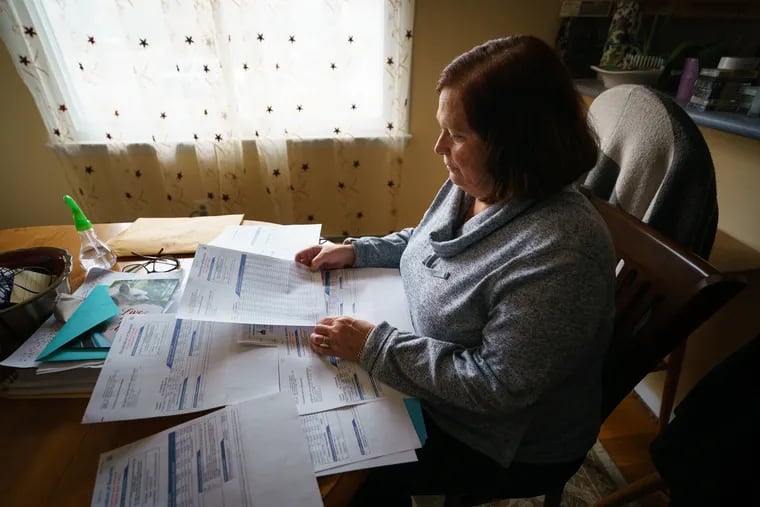 Trish Martin, 54, of Horsham, shown on October 29, 2019 with medical bills she received after she realized she had bought a limited-benefit insurance plan - not the full health insurance she thought she was getting.