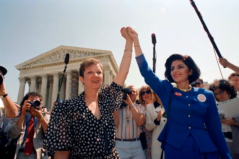 Norma McCorvey, also known as Jane Roe in the 1973 court case, left, and her attorney Gloria Allred hold hands as they leave the Supreme Court building in Washington after sitting in while the court listened to arguments in a Missouri abortion case, on April 26, 1989.