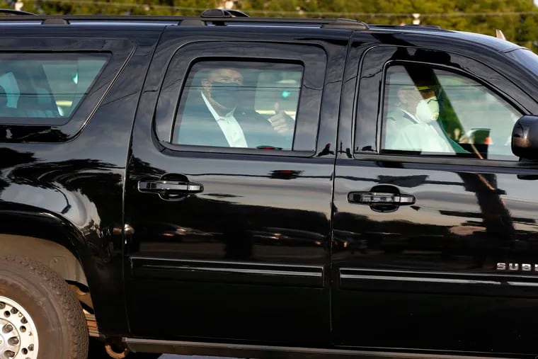President Donald Trump offers a thumbs up to his supporters from a motorcade outside Walter Reed Medical Center on Sunday.