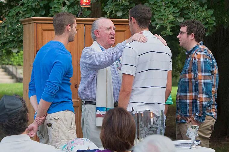 At Congregation Kol Ami in Elkins Park, Rabbi Elliot Holin blesses his youngest son, Josh, 20, a junior at the University of Miami, as Josh's brothers David (left) and Jonathan look on.