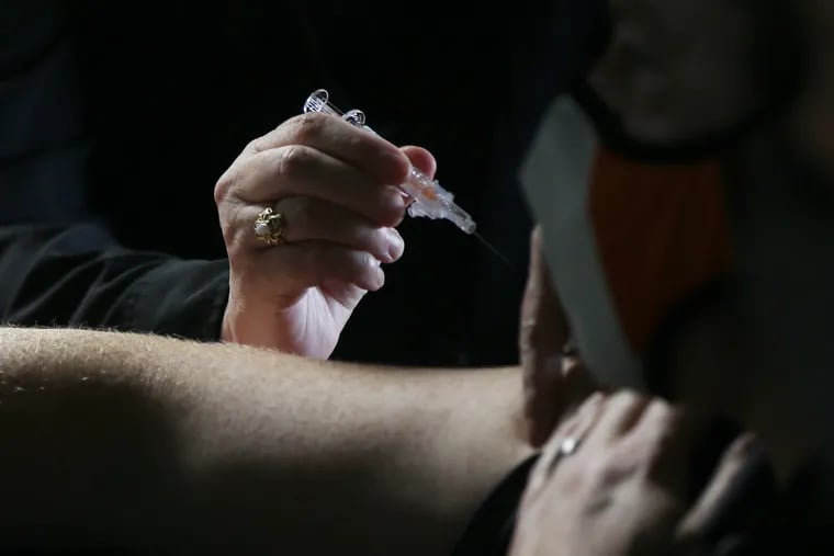 Volunteer Kathy Sullivan, a retired nurse, prepares to administer a flu shot during a drive-through clinic for police officers and their family members at the Delaware Valley Intelligence Center in South Philadelphia in October.  The clinic was the last of three such events organized this year by the city health department and Law Enforcement Health Benefits.