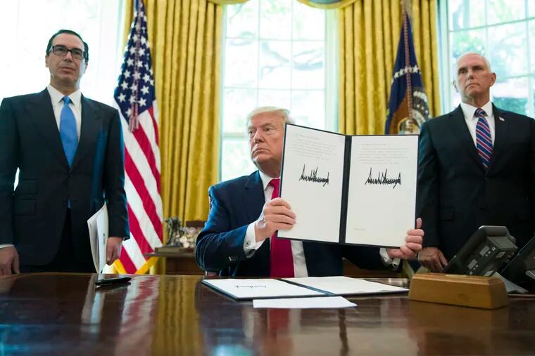 President Donald Trump holds up a signed executive order to increase sanctions on Iran, in the Oval Office of the White House, Monday, June 24, 2019, in Washington. Trump is accompanied by Treasury Secretary Steve Mnuchin, left, and Vice President Mike Pence.