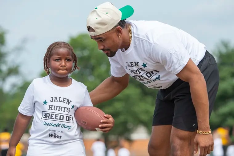 Eagles quarterback Jalen Hurts encourages a youngster during agility drills at his football camp at Cheltenham High School on Saturday.