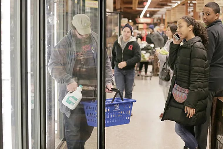 Shoppers empty the dairy cases while brother and sister Kaya and
Ken Strother (right) of Cherry Hill, N.J., were sent to the store by their
mother for almond milk at Wegmans in Cherry Hill on Jan. 25, 2015.
Kaya was not sure what to get so she was on the phone with mom.  (Elizabeth Robertson/Staff Photographer)