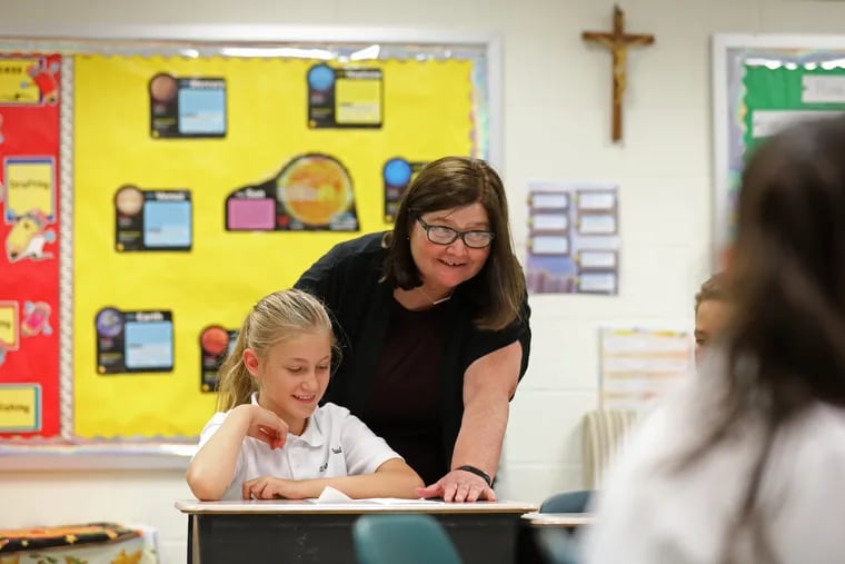 Principal Peg Egan helps fifth-grader Lucy Charleton at Sts. Peter and Paul School.