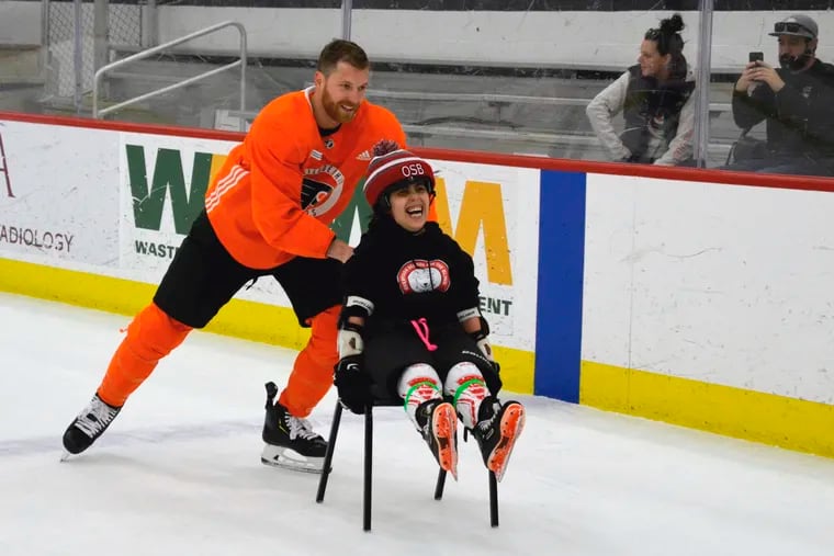Stephanie Algarian, a student at Overbrook School for the Blind, shares a laugh with Flyers captain Claude Giroux on Wednesday at the Skate Zone in Voorhees.