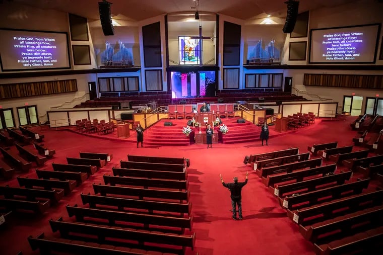 Reverend Dr. Alyn E. Waller (bottom right) leads his three-member choir from the main aisle of a largely empty Enon Tabernacle Church in North Philadelphia during the church’s livestreaming Easter Sunday service.