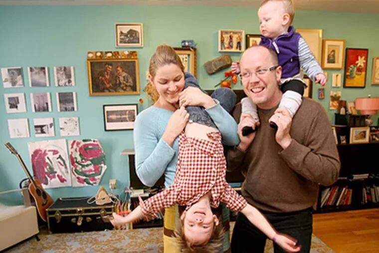 Liz Kinder, left, and Tim McDonald clown around with 2 of their 3 children in the living room of their home. ( Charles Fox / Staff Photographer )