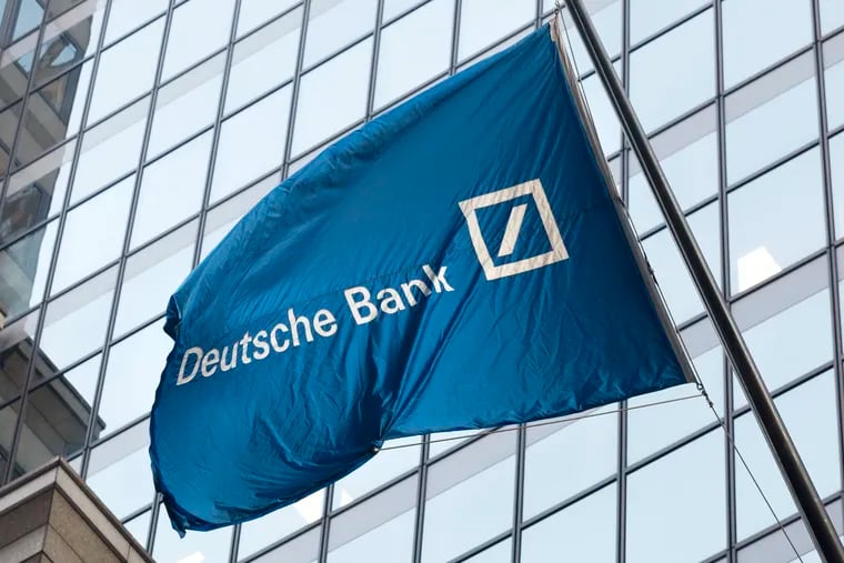 File photo shows a flag for Deutsche Bank flying outside the German bank's New York offices on Wall Street. Recently published book "Dark Towers" shines a light on Deutsche Bank — financier of Trump, Kushner, and Russian oligarchs.