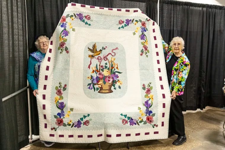 Beverley MacGown (right) and longtime friend and fellow quilter Jean Donahue (left), both of Concord, N.H., hold up MacGown’s quilt, "Baskets & Butterflies," during the Pennsylvania National Quilt Extravaganza at the Greater Philadelphia Expo Center in Oaks, Pa., last weekend. The quilt won a blue ribbon at the 2004 Vermont Quilt Festival.