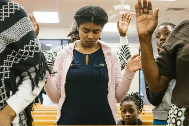 Enshyla Ulysse, along with members of the Haitian community, pray at  First Haitian Church of God of Prophecy in West Oak Lane before an information meeting on Saturday, May 13.