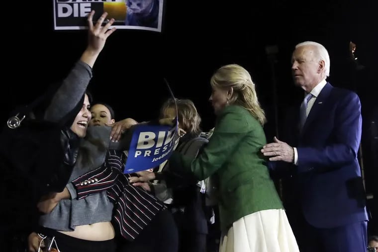 A protester at left, is held back by Biden adviser Symone Sanders, wearing stripes, and Jill Biden, second from right, as Democratic presidential candidate former Vice President Joe Biden stands during a rally.