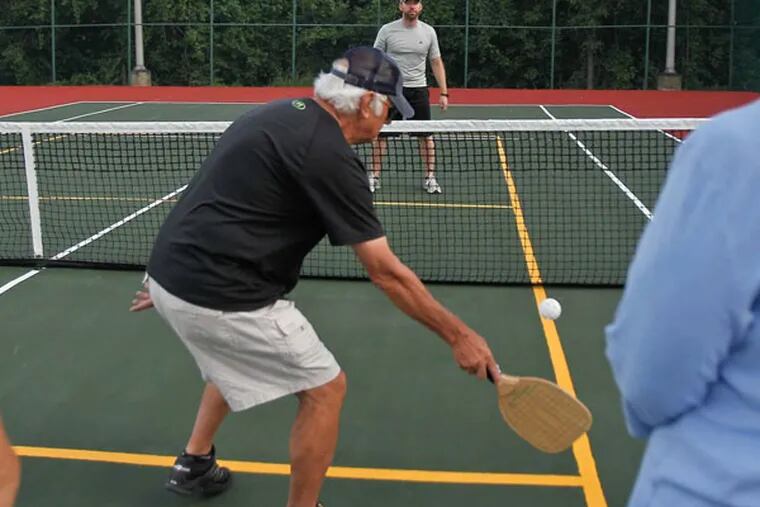 Dan Marlowe, center, demonstrates a strategic shot with instructor Jay Hubert, center back, as others look on during a pickleball class at Kennedy Recreation Complex in St. Louis on July 15, 2014. The class, offered by St. Louis Community College, has grown in popularity. (Sarah Conard/St. Louis Post-Dispatch/MCT)
