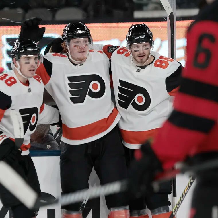 The Flyers' Morgan Frost (left) and Joel Farabee (right) celebrate Owen Tippett’s second goal against the Devils at MetLife Stadium on Saturday.
