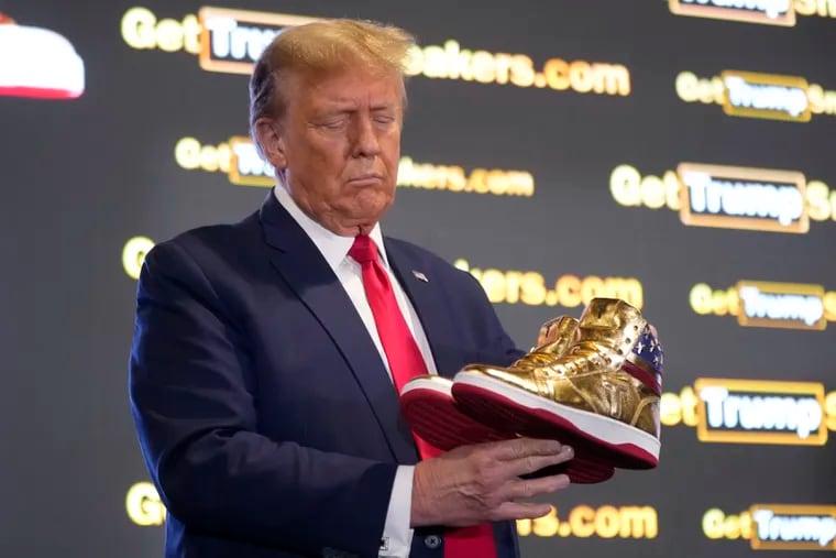 Republican presidential candidate former President Donald Trump holds gold Trump sneakers at Sneaker Con Philadelphia, an event popular among sneaker collectors on Saturday, Feb. 17, 2024. Photo by Manuel Balce Ceneta / AP