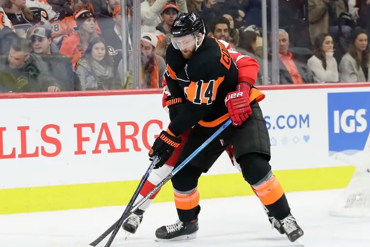 Flyers center Sean Couturier shields Detroit's Madison Bowey from the puck in an early-season game.