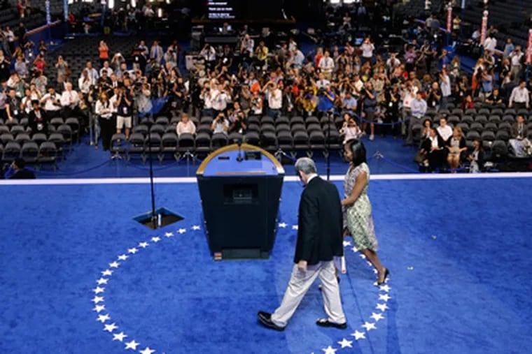 First Lady Michelle Obama walks to center stage with a production manager during a sound check for the Democratic National Convention in Charlotte, N.C., on Monday, Sept. 3, 2012. (AP Photo/Charlie Neibergall)