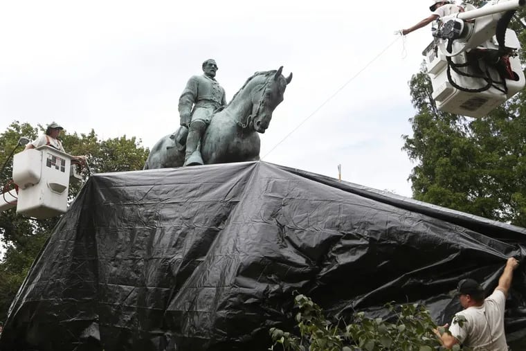 In this Wednesday, Aug. 23, 2017, file photo, City workers drape a tarp over the statue of Confederate General Robert E. Lee in Emancipation park in Charlottesville, Va.