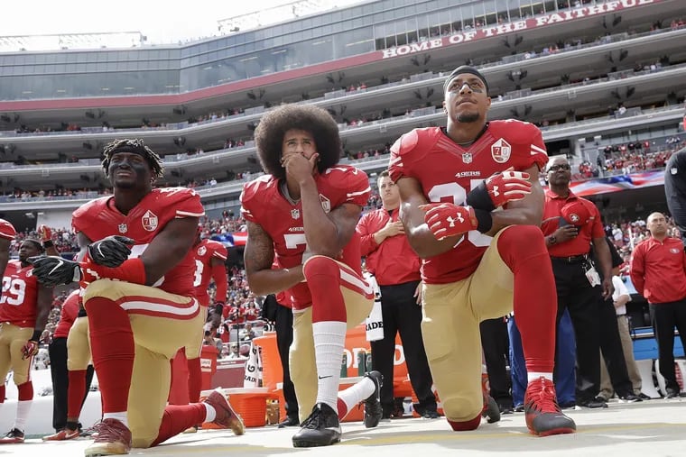 In this Oct. 2, 2016 file photo, from left, San Francisco 49ers outside linebacker Eli Harold, quarterback Colin Kaepernick and safety Eric Reid kneel during the national anthem before an NFL football game against the Dallas Cowboys in Santa Clara, Calif.