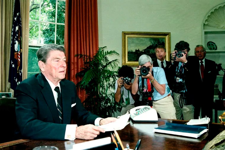 In this June 25, 1986 file photo, U.S. President Ronald Reagan appeals to the House of Representatives for their support in approving aid to Nicaraguan rebels in a televised speech from the Oval Office at the White House in Washington, D.C. White House spokesman Larry Speakes, third from right, and White House Chief of Staff Donald Regan, right, look on from behind photographers.