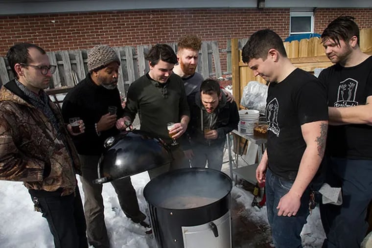 The crews from Pizza Brain and Tired Hands Brewery gather around the smoker as they prepare smoked sea salt in back of Tired Hands Brewing on Jan. 27, 2014 in Ardmore, Pa. Pizza Brain, in Fishtown, is teaming up with Tired Hands Brewing, in Ardmore, to collaborate on a pizza, a beer and an ice cream. ( ALEJANDRO A. ALVAREZ / STAFF PHOTOGRAPHER )