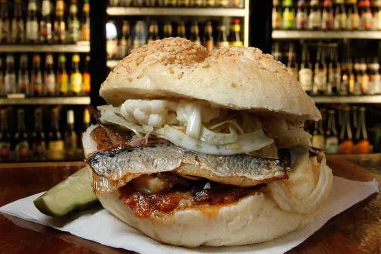 The Seared Sardine Sandwich at The Corner Foodery, with some of the 600-plus beers in refrigerators behind.