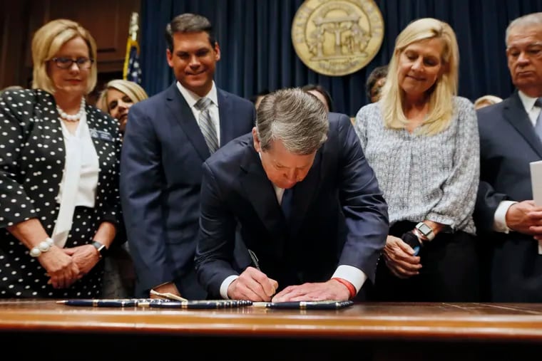 Georgia’s Republican Gov. Brian Kemp, center, signs legislation on May 7 banning abortions once a fetal heartbeat can be detected.