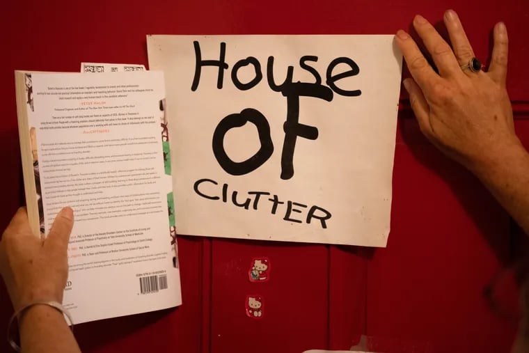 A woman shows off a sign taped to her front door reading in East Kensington.