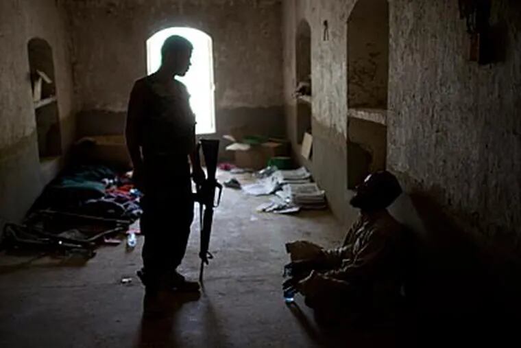 An Afghan soldier stands guard next to a  villager who was detained at COP Nolen due to trace amounts of ammonium nitrate found on his fingers in Kandahar, Afghanistan on July 25. (AP Photo/Rodrigo Abd)