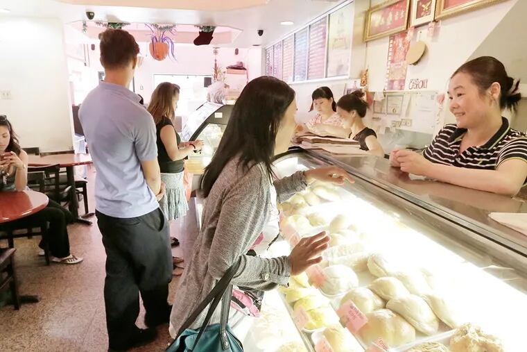 Suchang Ma (far right) waits on customers at the Mong Kok Station bakery in Phila. on August 7, 2015.( ELIZABETH ROBERTSON / Staff Photographer )