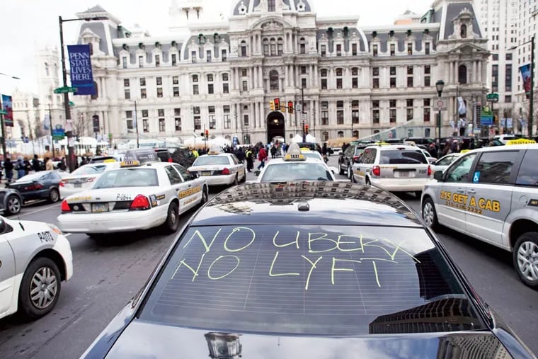 Taxis and Uber Black cars - one with a message - park in front of City Hall as their drivers demand better regulation of Uber X.
