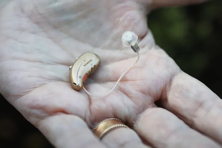 B.J. Kittredge displays her hearing aid, which is easy to remove and barely noticeable. The smaller part goes into her ear while the larger part rests on the back of her earlobe.