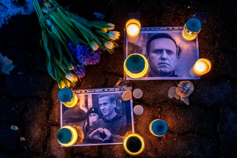 Photos of jailed Russian opposition leader Alexei Navalny with flowers and candles are laid on a ground in front of the Russian embassy in Vilnius, Lithuania, Feb. 16.