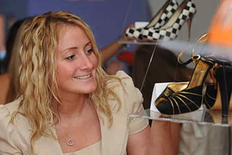Liz  Johnson of Mays Landing checks out Stephanie LaGrossa's size 7's at last week's auction, which raised money for women battling cancer. (Bob Williams / For the Inquirer)
