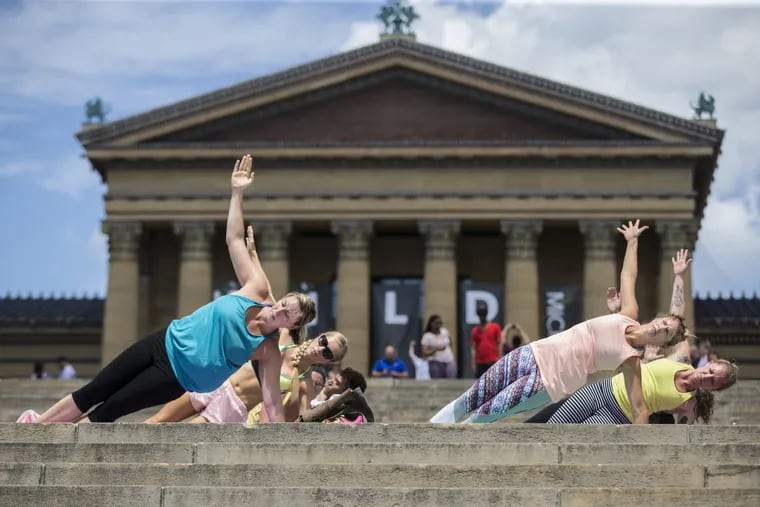 In June, Maura Kennedy, from Moorestown, NJ, left, and Jen Knoll, from South Jersey, right, and 100 other people perform the side plank pose during a pop up yoga session on the Art Museum steps, held by Torc Yoga of Philadelphia.