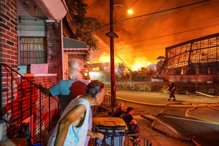 Residents on Judson Street watch as firefighters battle a six-alarm warehouse fire in the Nicetown-Tioga neighborhood in the early morning of Aug. 23, 2020.