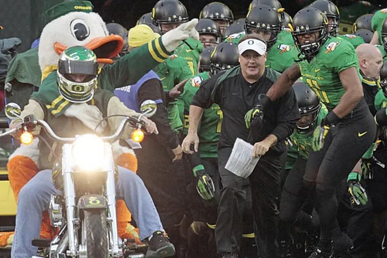 Oregon coach Chip Kelly, center, leads his team onto the field for an NCAA college football game against California in Eugene, Ore. Kelly announced Monday, Jan. 23, 2012, that he's remaining with the Ducks, though he says he was flattered by the interest shown in him by the NFL's Tampa Bay Buccaneers. (AP Photo/Don Ryan, File)