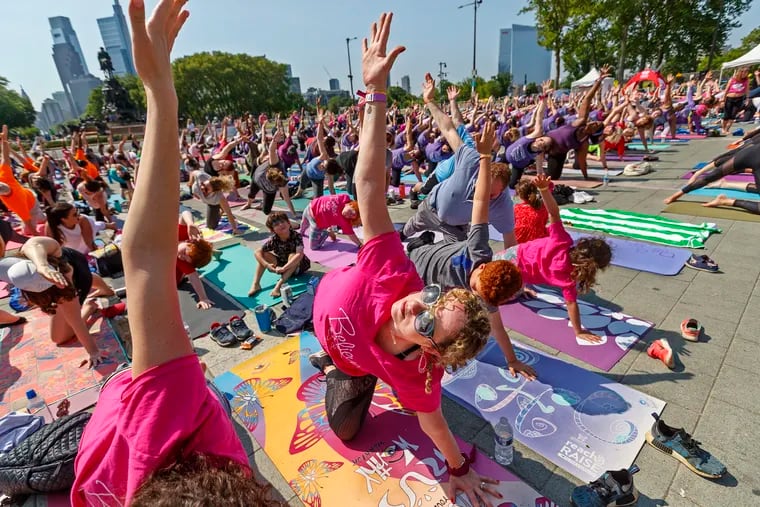Breast cancer survivor Marisa Gefen (center) strikes a yoga pose with thousands of other participants in the Living Beyond Breast Cancer's Reach & Raise event on the Art Museum steps on Sunday.