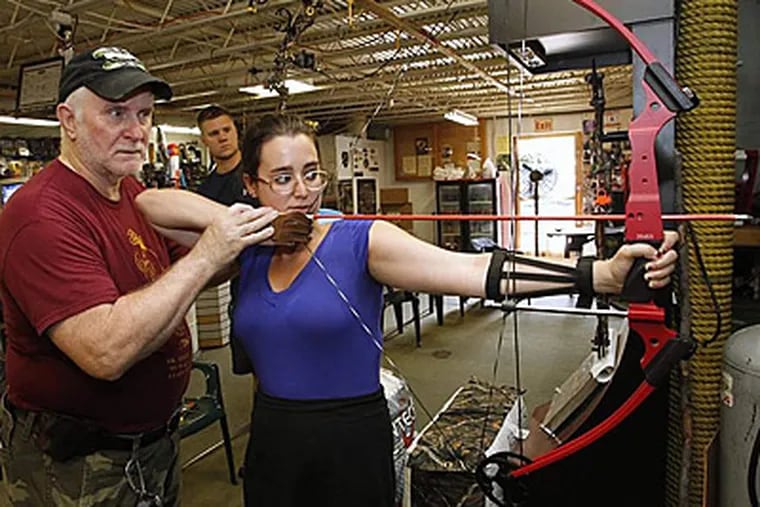 Molly Eichel gets tips from B&A Archery's Bill Arrow while Jonathan Papelbon looks on. (Alejandro A. Alvarez/Staff Photographer)