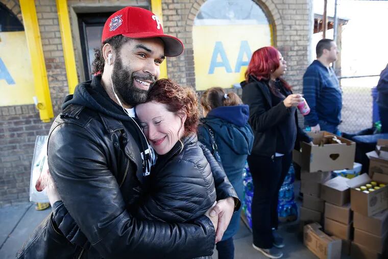 Ryan Banks, left, who is the owner of Famjuice, hugs Margaux Murphy, founder of the group, Sunday Love project as they feed people outside the Last Stop Recovery House in Philadelphia on Christmas Day.
