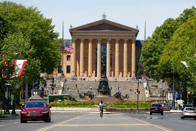 A jogger runs in the middle of the Benjamin Franklin Parkway with the Philadelphia Museum of Art in the background.
