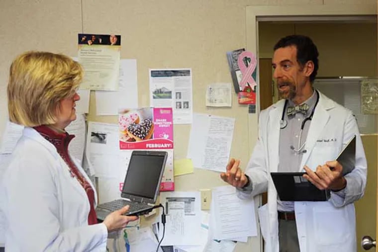 Dr. Daniel Wolk (right), 58, family medicine, talks with one of his partners Dr. Margaret Walker, an internist, in their practice in Broomall, Feb. 25, 2014.  Wolk convinced his three partners in the practice to follow the medical home model, which encourages primary care providers to play a role in all aspects of their patients' care, from hospitalizations to seeing specialists.  ( CLEM MURRAY / Staff Photographer )