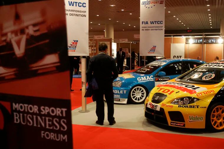 At a business forum in Monaco, a visitor looks at World Touring Car Championship vehicles.