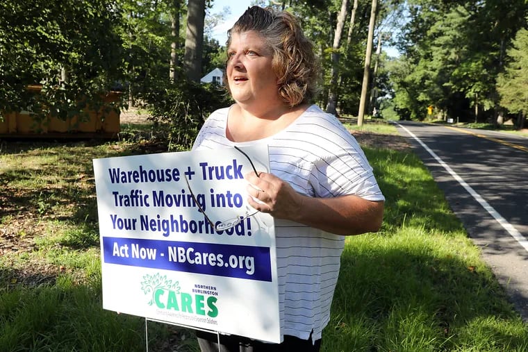 Beth Camp, who helped organize NBCares, shows a sign she planted in front of her family home to work against an onslaught of tractor trailers that could have come down her street from a giant warehouse project in Mansfield Township, N.J.