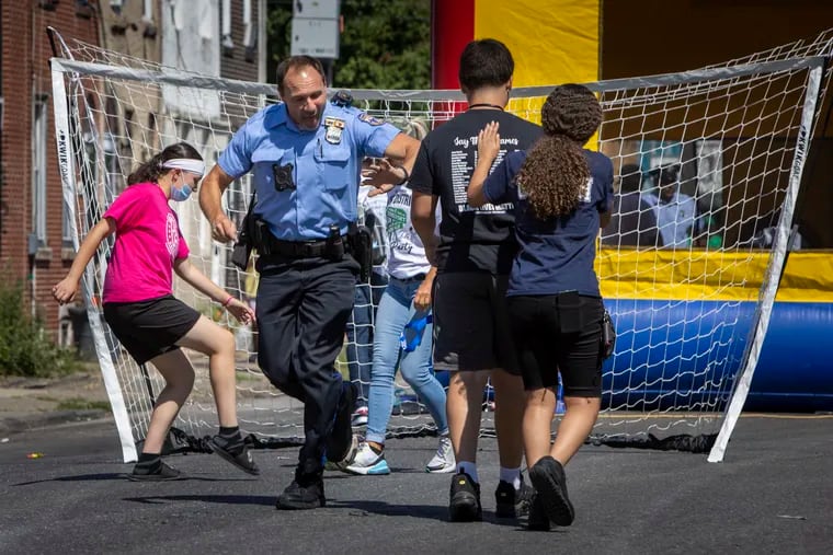 Police officer John Rajkowski with 24th District high fives Jeremiah Tovar, 15 during a quick game of soccer along E. Somerset. Rajkowski played soccer as a youth at the Boys Club and Father Judge High School. Jeremiah plays with the Kensington Soccer Club.