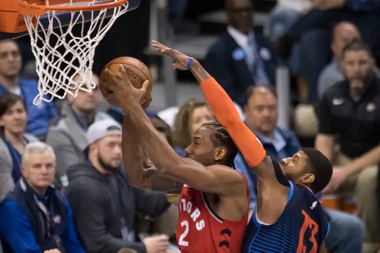 Toronto Raptors forward Kawhi Leonard (2) shoots while defended by Oklahoma City Thunder forward Paul George (13) during the first half of an NBA basketball game Wednesday, March 20, 2019, in Oklahoma City.
