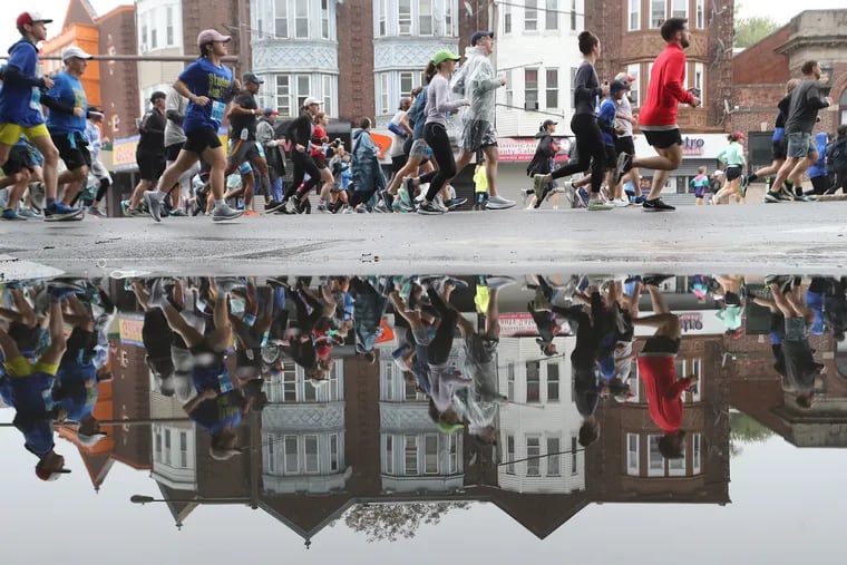 Runners are reflected in a puddle at Broad Street and Windrim Avenue during the 43rd annual Independence Blue Cross Broad Street Run in Philadelphia.