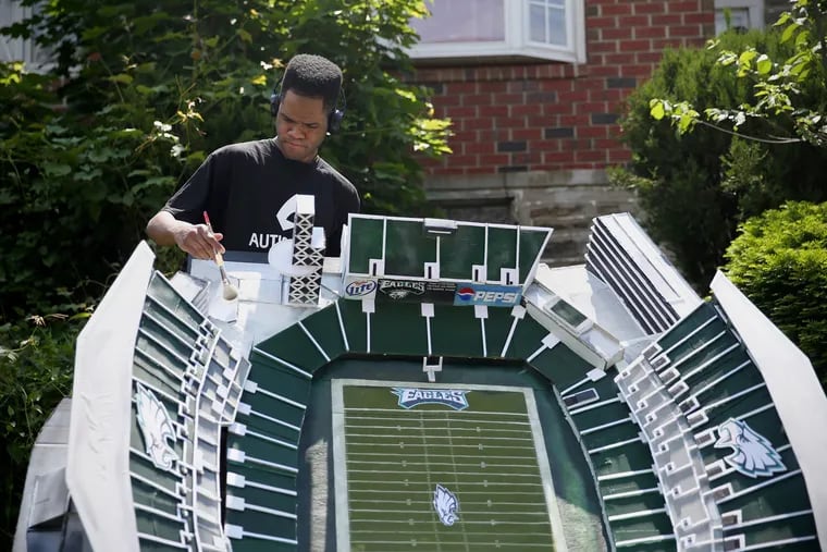 Kambel Smith dusts off his model of Lincoln Financial Field before transporting it to be displayed at the Eagles Autism Challenge.