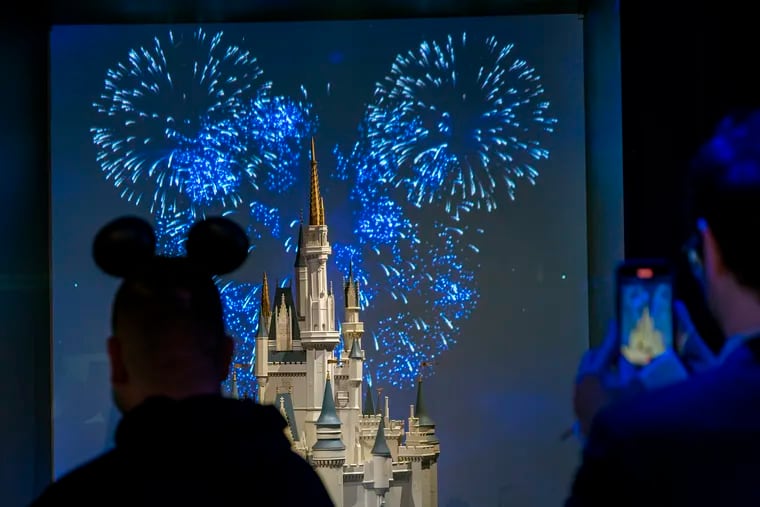 Guests watch a video of fireworks shown behind a model of the Cinderella Castle display at the Franklin Institute during Wednesday's preview of "Disney100: The Exhibition," celebrating 100 years of the Walt Disney Co.